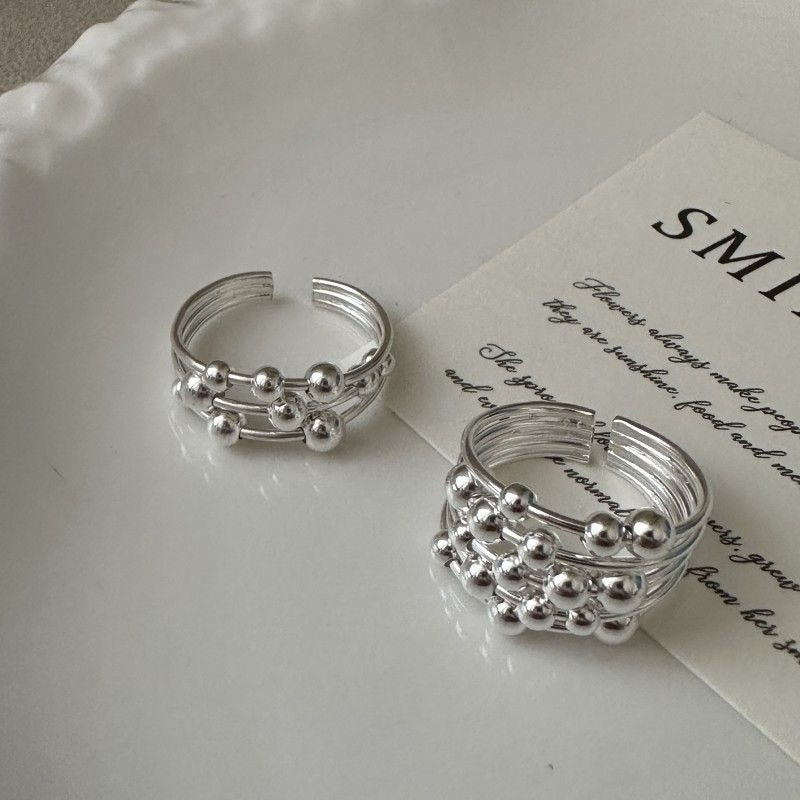 To smalle ringe i sølvfarve med små kugler langs båndet