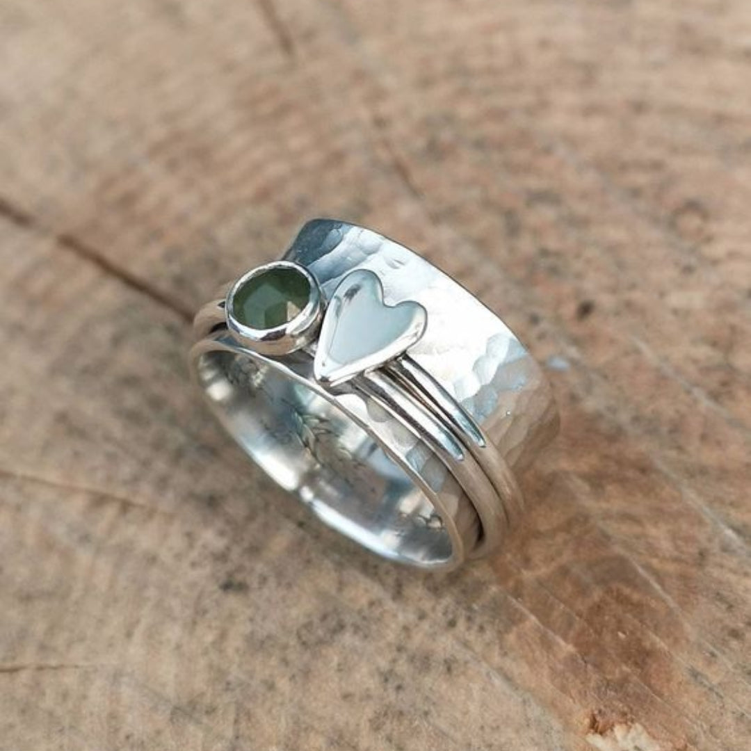 Bred ring i sølvfarve med hjerte og rund grøn sten
