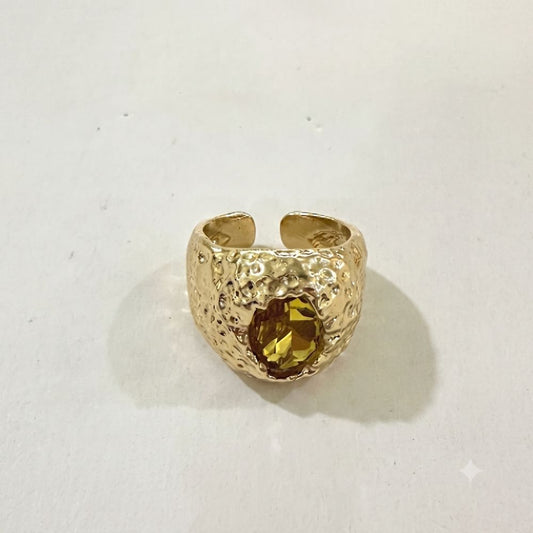 Åben ring i guldfarve med hamret overflade og gul sten